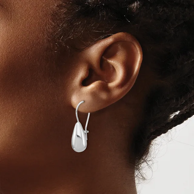 A person wearing a silver teardrop-shaped earring with a hook fastening, shown from the side view against their ear.