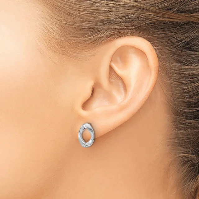 A person wearing a small oval silver hoop earring in their pierced earlobe, shown in profile from the side of their head and neck.