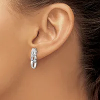 A woman wearing a chunky silver chain link hoop earring in her earlobe, shown in profile against her neck and shoulder.