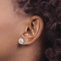 A person wearing a single round diamond stud earring in their pierced earlobe, shown in profile view against their shoulder and dark curly hair.