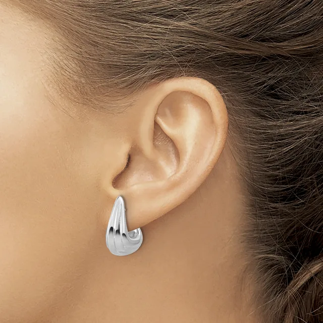 A person wearing a polished silver teardrop-shaped hoop earring in their earlobe, shown from the side profile.