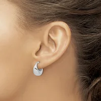 A person wearing a polished silver chunky curved hoop earring in their ear lobe.
