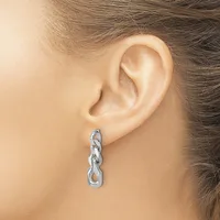A silver chain link drop earring hangs from the earlobe of a person shown in profile view.