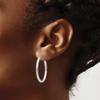 A person wearing silver hoop earrings, shown from the side profile focusing on the ear and earrings against their brown skin tone.