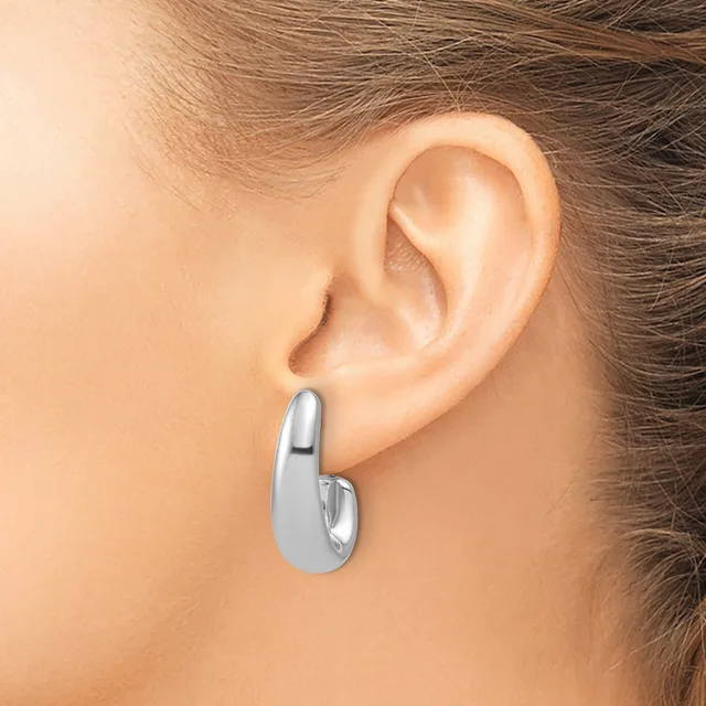 A polished silver chunky curved hoop earring worn on a model's earlobe, shown from a side profile view.