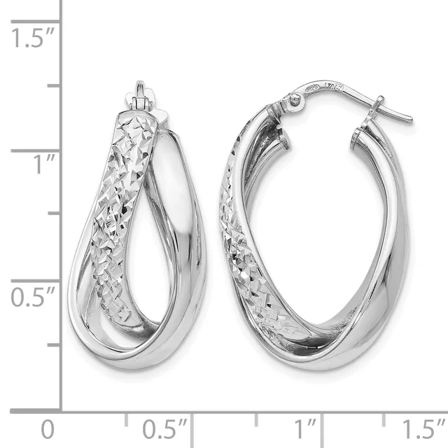 A pair of silver hoop earrings with textured and polished surfaces, displayed next to a ruler showing they measure approximately one inch in length.