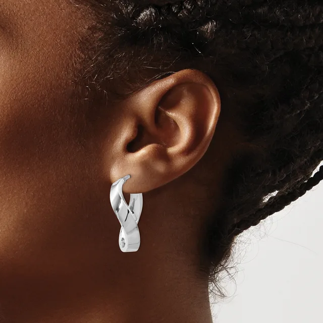 A person wearing a silver twisted hoop earring in their earlobe, shown in profile against a neutral background.