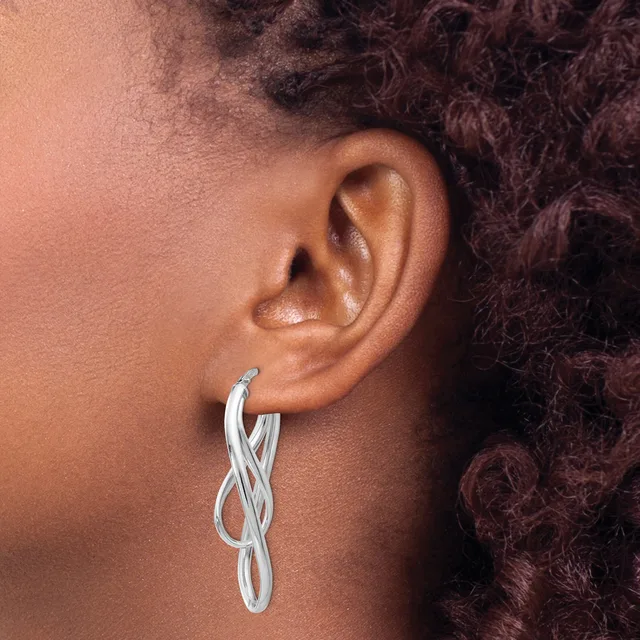 A person wearing a twisted silver hoop earring in their earlobe, shown in profile against their shoulder and dark curly hair.