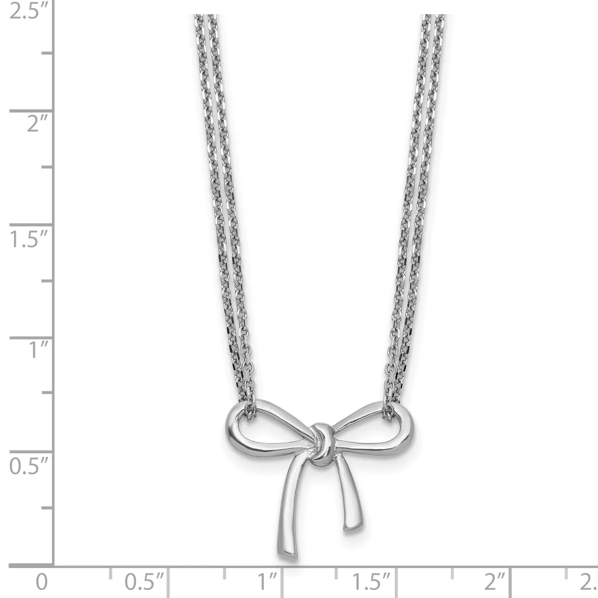 Silver bow-shaped pendant hanging from two delicate chain strands, displayed against a ruler showing the necklace is approximately 2.5 inches long.