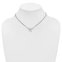 A silver-toned necklace with a delicate bow pendant displayed on a white mannequin bust.