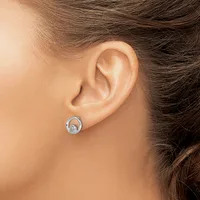 A silver stud earring with a circular bezel setting containing a light blue stone worn on a person's earlobe.
