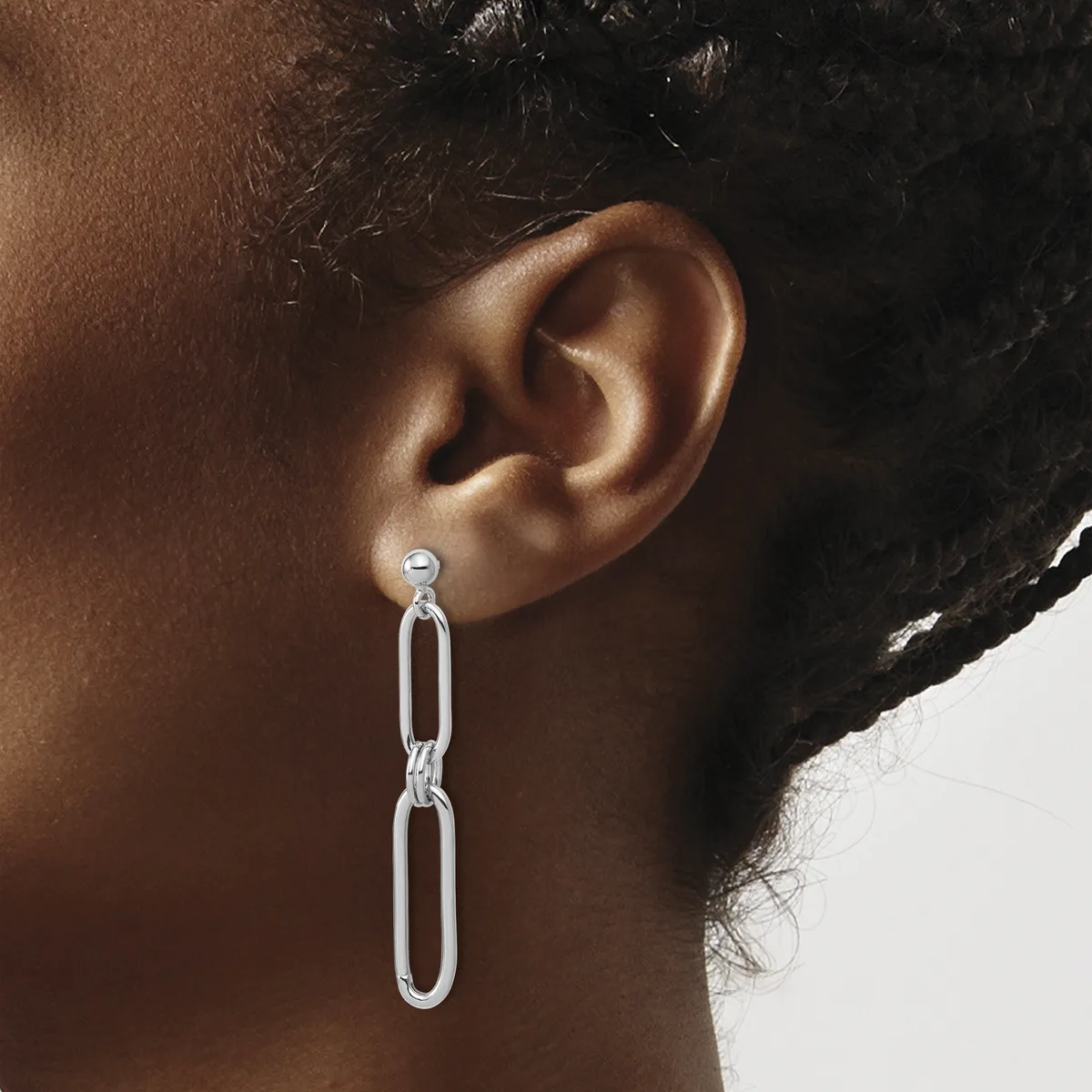 A person wearing a long silver chain link dangle earring with an oval connector detail, shown from the side against a neutral background.