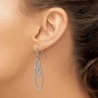 A person wearing a pair of silver-toned dangle earrings with interlocking oval links studded with small crystals or rhinestones.