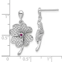 Silver four-leaf clover pendant earrings with cubic zirconia stones and a small pink ruby center stone, shown on a measurement scale.