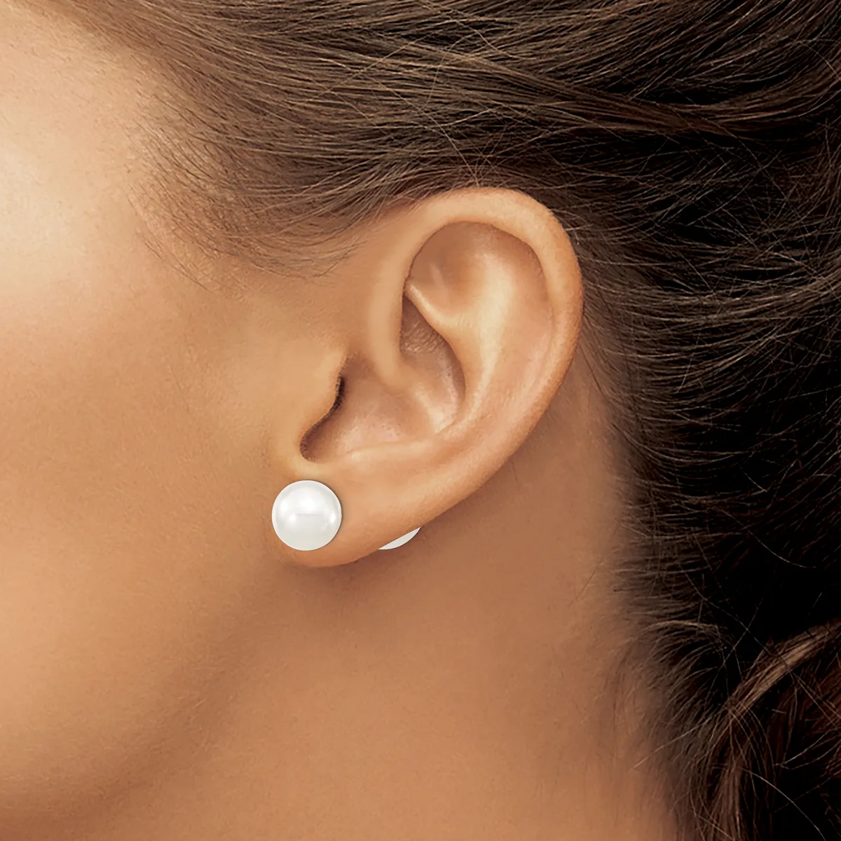 A person wearing a small white round pearl stud earring in their earlobe, shown in profile view.