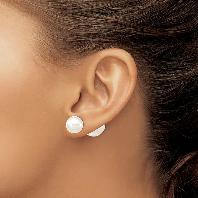 A person wearing small white circular stud earrings in both earlobes, shown from the side view of their ear and neck.
