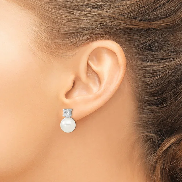 A woman wearing a pearl drop earring with a square-cut diamond or crystal stud top, shown from the side profile against her ear.