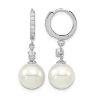 A pair of silver huggie hoop earrings with diamond-paved tops and white pearl drops, shown from the front and side.