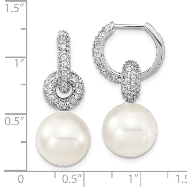 A pair of silver hoop earrings with cubic zirconia-paved dome tops and dangling white pearl drops, displayed on a measurement scale.