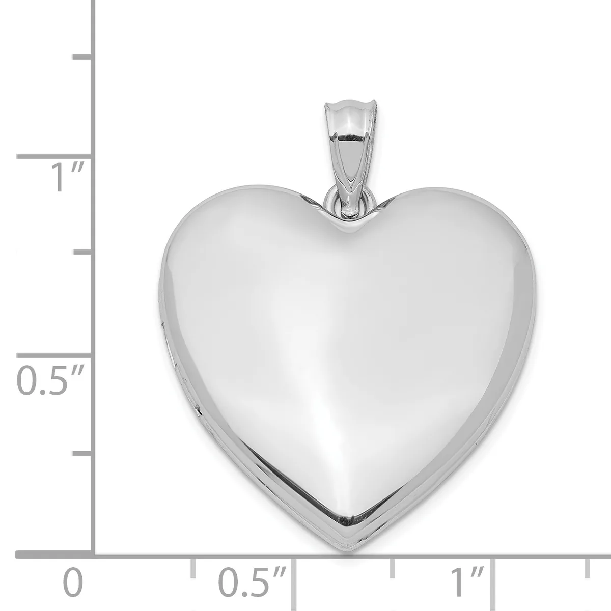 A polished silver heart-shaped locket pendant with a bail, shown against a measurement scale indicating approximately one inch in height.