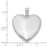 A polished silver heart-shaped locket pendant with a bail, shown against a measurement scale indicating approximately one inch in height.