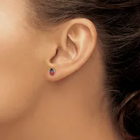 A close-up view of a person's ear wearing a small red and black ladybug-shaped stud earring.