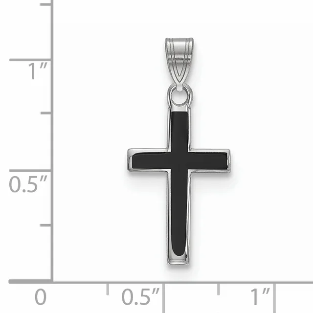A silver cross pendant with black enamel inlay shown against a ruler measuring approximately one inch tall by half an inch wide.