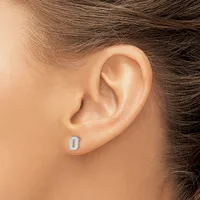 A person wearing a small rectangular silver stud earring in their earlobe, shown in profile against their neck and shoulder.