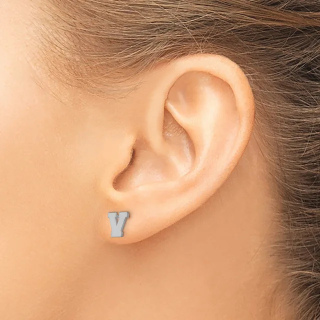 A small rectangular blue-grey stud earring worn in a pierced earlobe on a person with brown hair.
