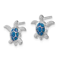 A pair of silver sea turtle stud earrings with blue opal inlay on the shells and textured silver details on the heads, flippers, and bodies.