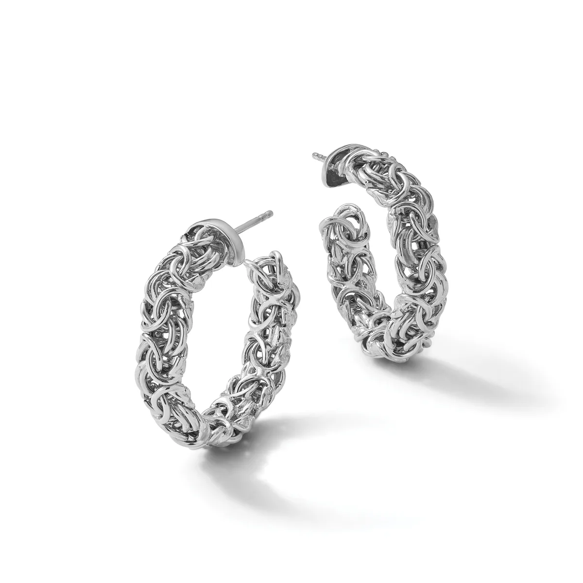 A pair of ornate silver hoop earrings with intricate braided and twisted textures throughout, displayed against a white background.