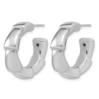 A pair of polished silver-toned chunky curved hoop earrings with hinged posts, shown from the front.