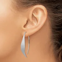 A person wearing a pair of silver curved drop earrings, shown from the side profile with one ear visible.