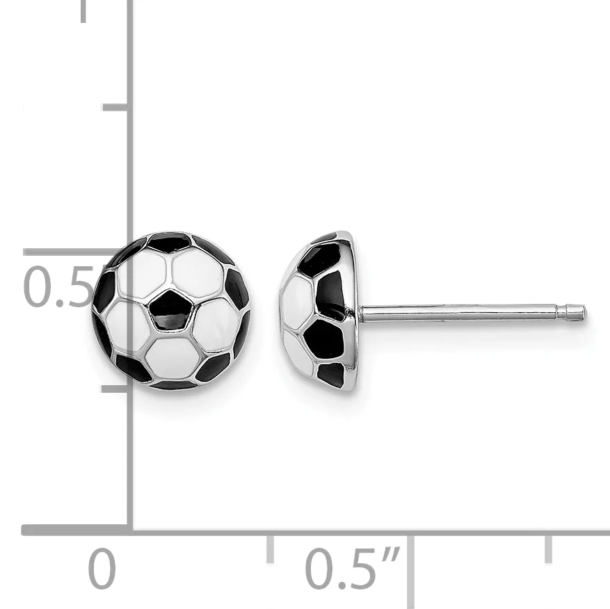 A pair of soccer ball stud earrings with black and white enamel panels on sterling silver posts, shown against a measurement scale.