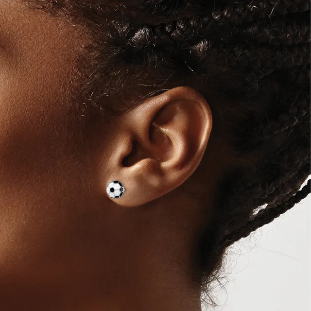 A close-up view of a person's ear wearing a small spherical stud earring with black and white soccer ball pattern design.