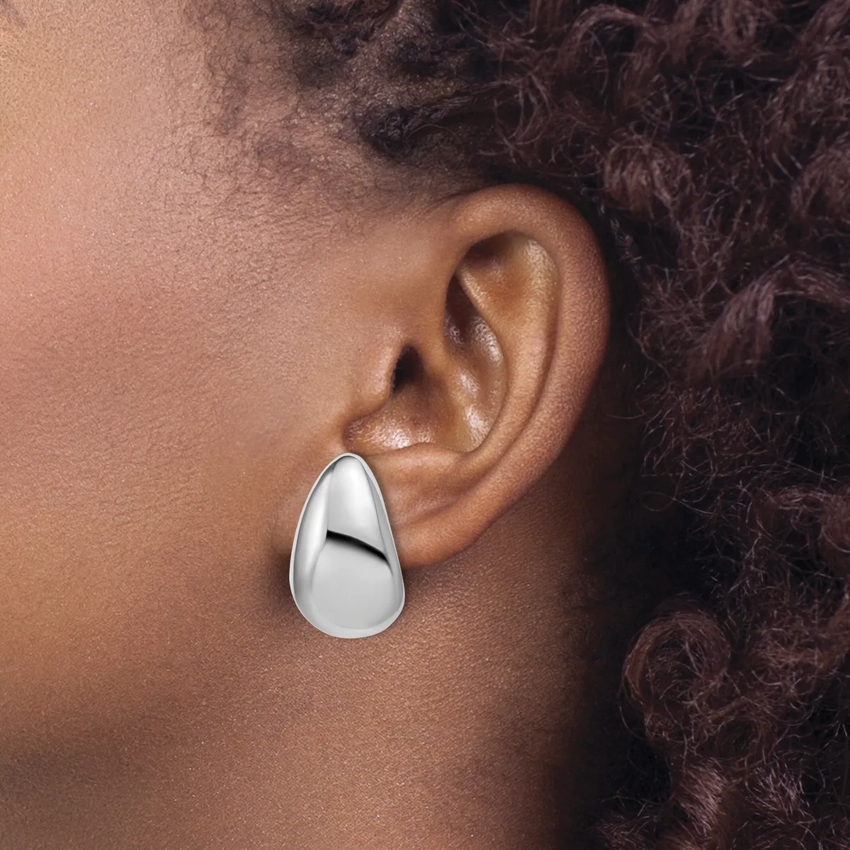 A polished silver teardrop-shaped earring worn on a person's earlobe, shown in profile view against their neck and shoulder.
