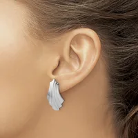 A silver ridged teardrop earring hanging from a pierced earlobe, shown from the side view of a person with brown hair.