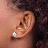 A person wearing a small round silver stud earring with a textured surface in their earlobe.