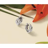 Two twisted silver hoop earrings displayed on a cream background with orange lilies and green leaves.