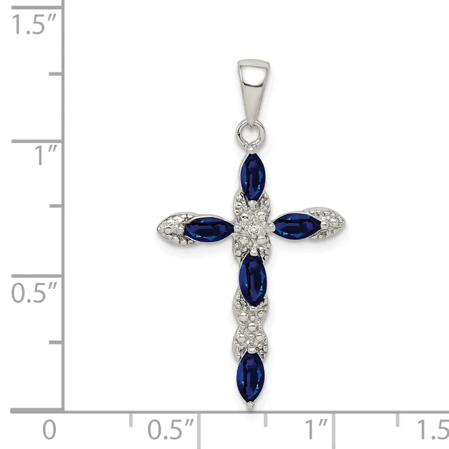 Silver cross pendant with five oval blue sapphires and diamond or crystal accents, displayed against a ruler showing approximately 1.25 inches in length.