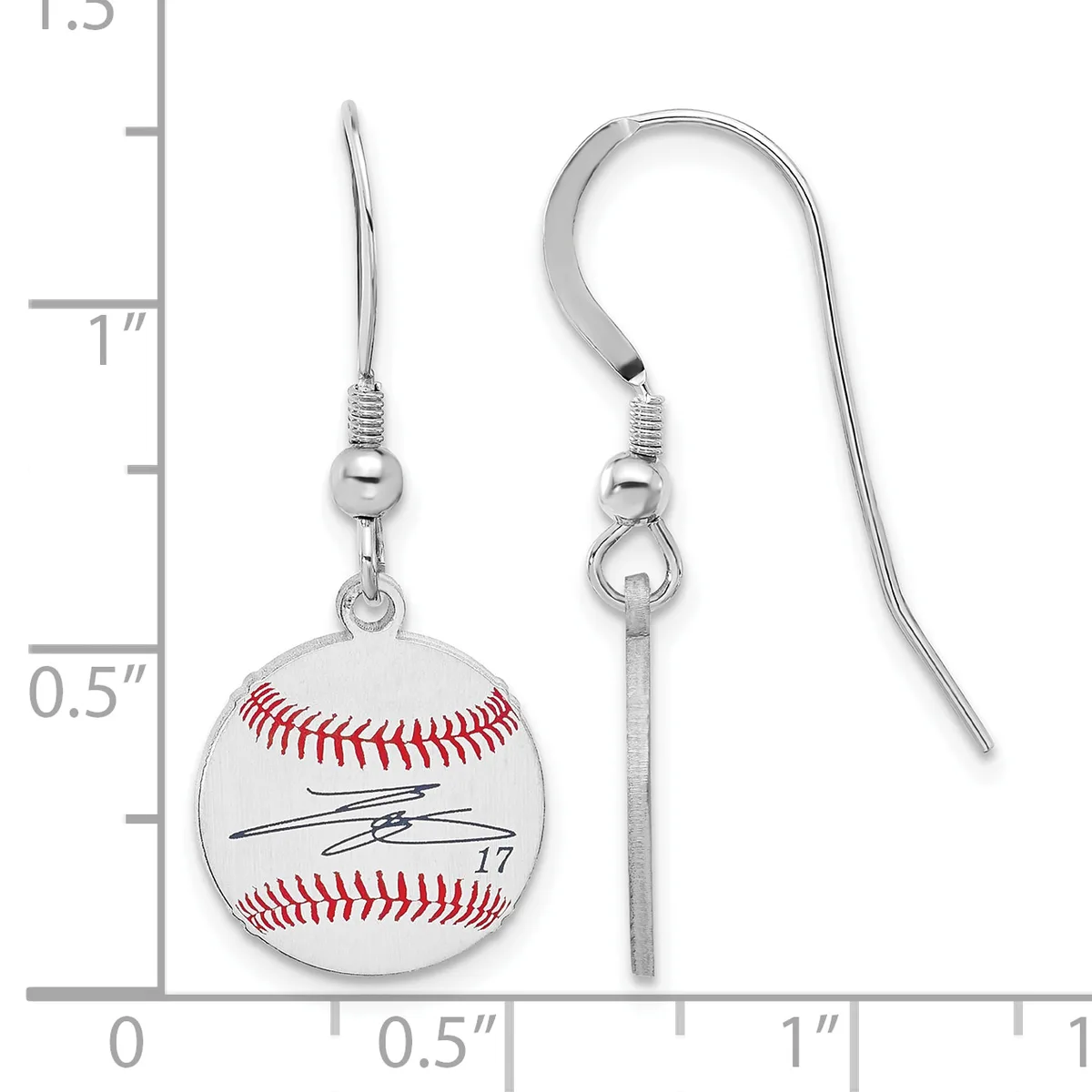 Pair of silver-toned baseball earrings with red stitching and a signature, suspended from curved ear wires, shown against a measurement scale.