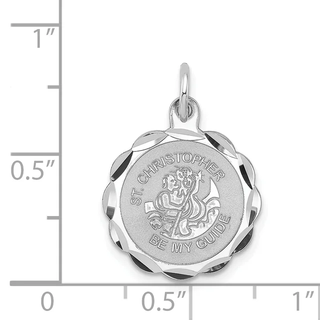 A silver round scalloped-edge pendant with engraved religious imagery and text, shown with a measurement scale indicating its size is approximately one inch in diameter.