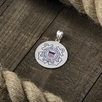 A round silver pendant featuring an engraved seal design with an anchor and shield, displayed on weathered wood with rope.