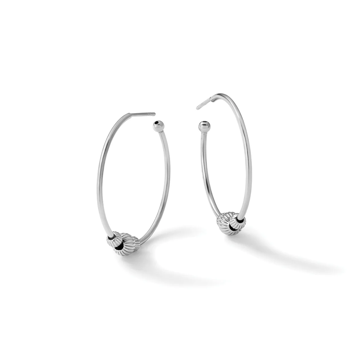 A pair of silver hoop earrings with textured spherical bead accents near the posts, displayed against a white background.