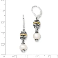 A pair of dangling earrings with ornate two-tone beaded caps and white pearl drops, displayed on a ruler showing approximately one inch in length.