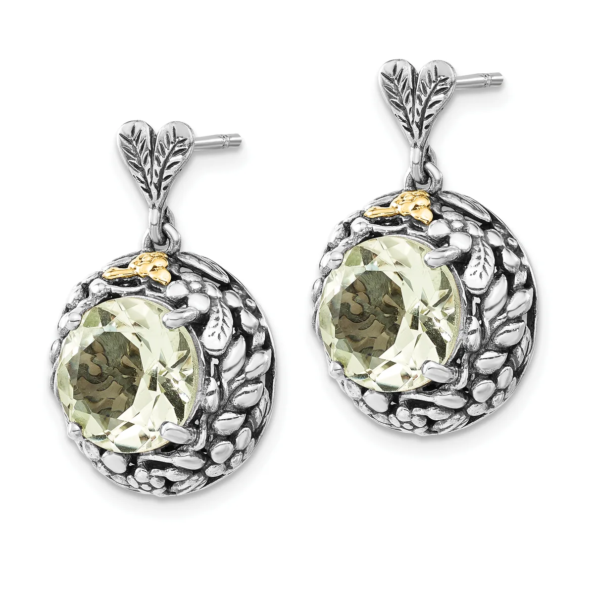 A pair of silver drop earrings with leaf-shaped posts, featuring pale green oval gemstones set in ornate round frames with textured metalwork and small gold accents.