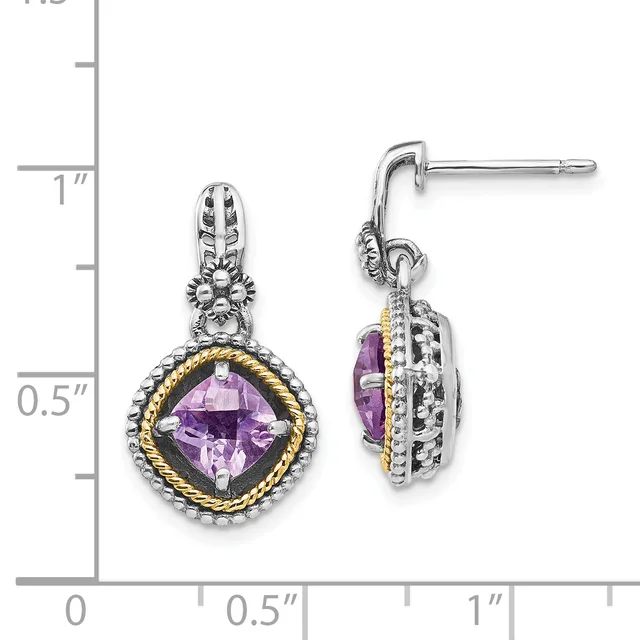 A pair of silver drop earrings with ornate tops, each featuring a cushion-cut purple amethyst surrounded by twisted gold and silver detailing, displayed next to a measurement scale.