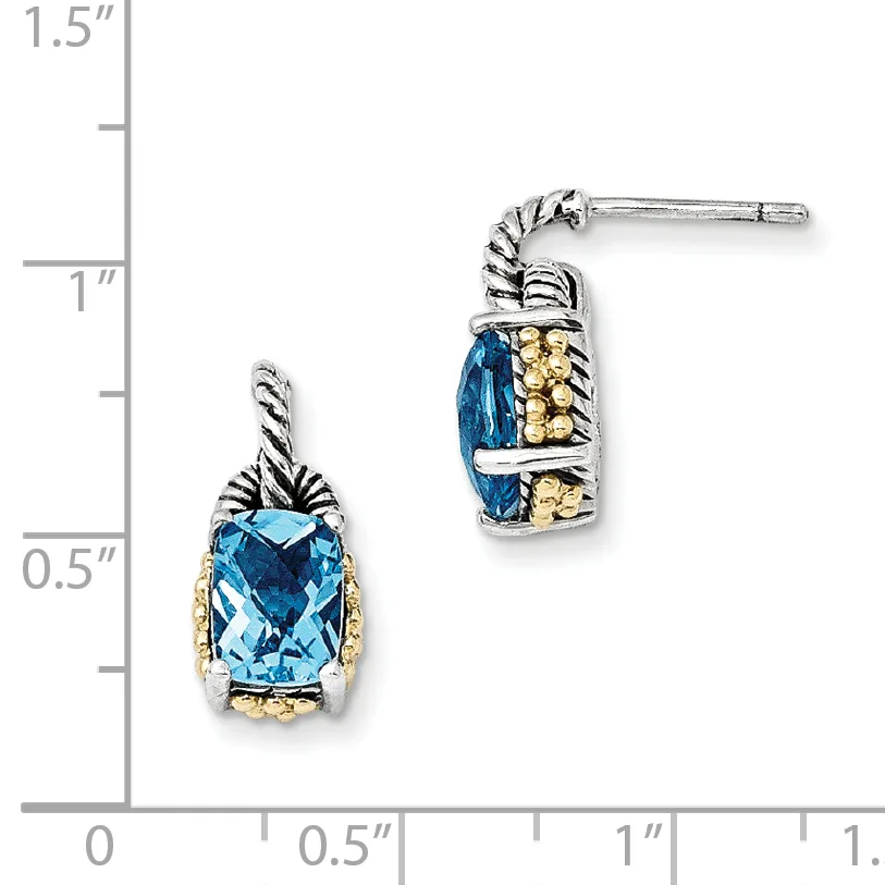 A pair of blue topaz earrings with twisted silver and gold-tone detailing, shown next to a measurement ruler indicating approximately one inch in height.