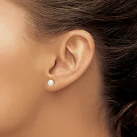 A person wearing a small white pearl stud earring in their earlobe, shown in profile against their neck and shoulder with dark hair pulled back.