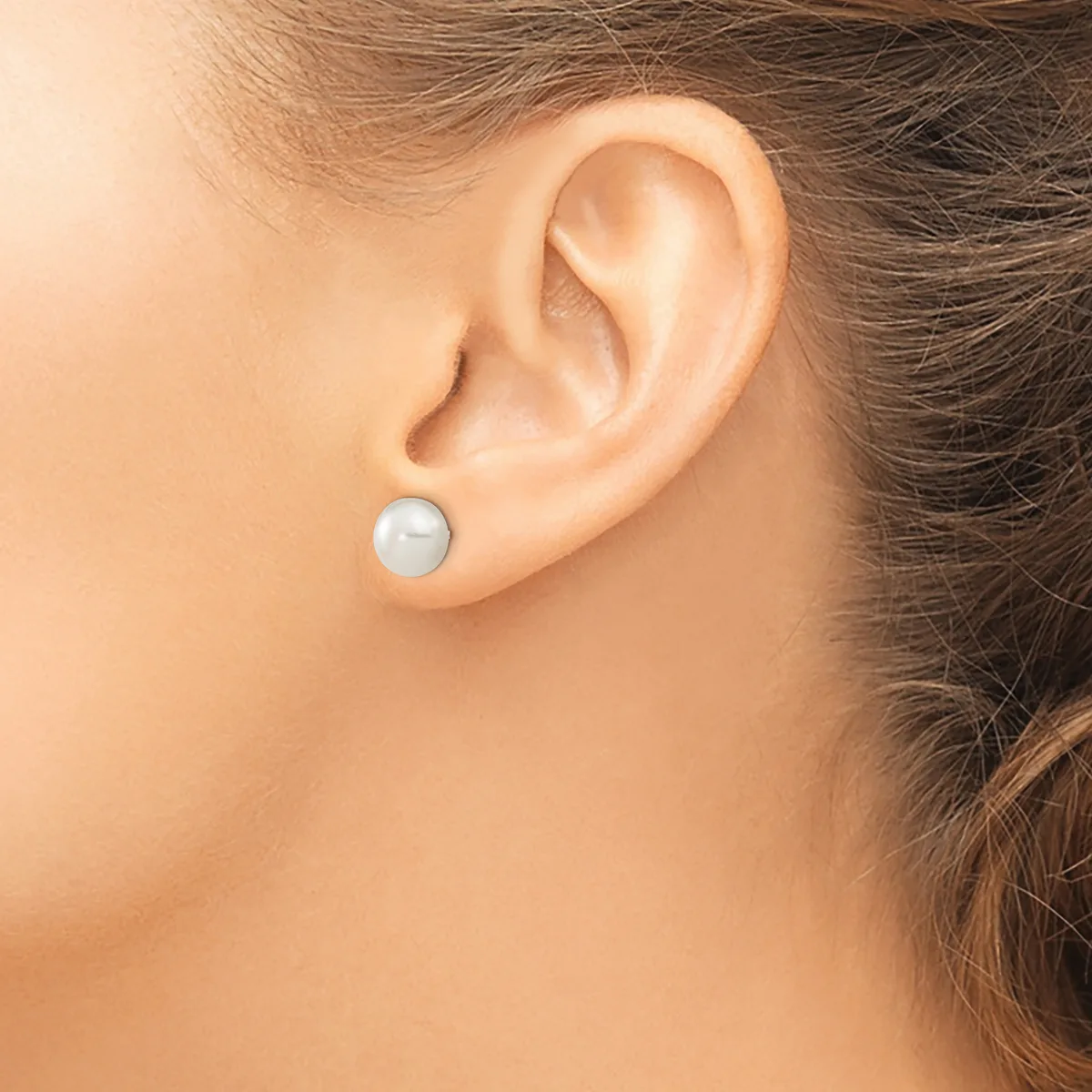 A person wearing a single pale blue pearl stud earring in their earlobe, shown in profile against their bare shoulder.